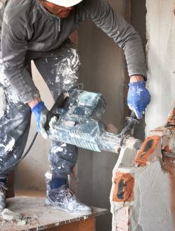 worker-drilling-wall-with-hammer-drill-in-building-2023-11-27-04-50-58-utc